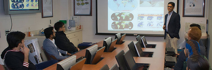 Meeting room where someone is presenting to a group of people that are sitting at a table