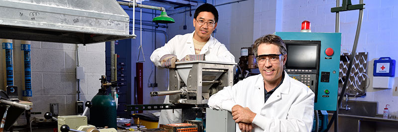 Professor and student standing next to machinery
