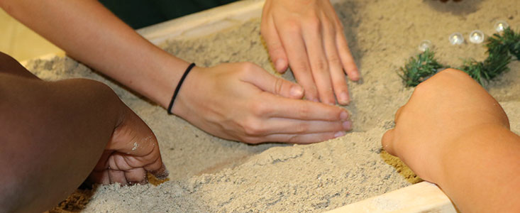 Student hands molding in a sandbox