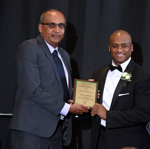 Aaron L. Copeland holding his Mechanical Engineering Distinguishes Alumni Award with Dr. Ranjan
