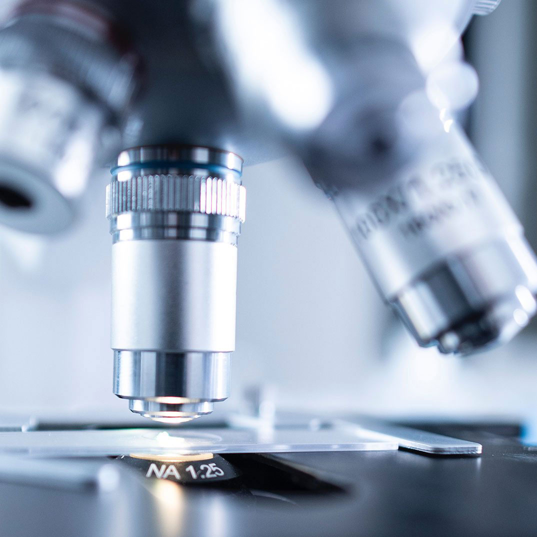 Microscope lens focused on a slide, showing close-up of the objective lens and stage