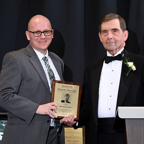 Ronald Flinn holding his award next to Peter Savolainen